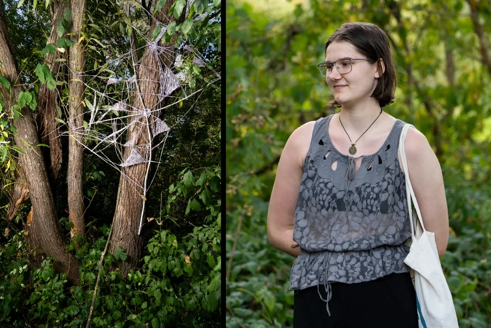 Dziewczyna patrzy na swoje dzieło. To pajęczyna rozciągnięta między drzewami.