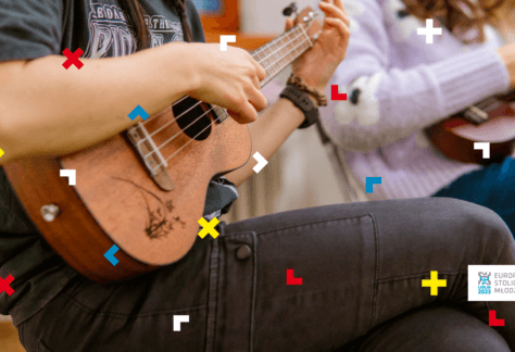 Dziewczyna siedzi z nogą założoną na nogę i gra na ukulele.