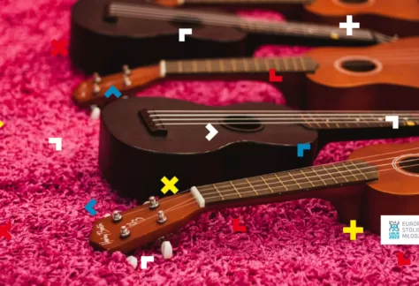 Na różowym dywanie leżą ukulele.