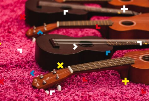 Na różowym dywanie leżą ukulele.