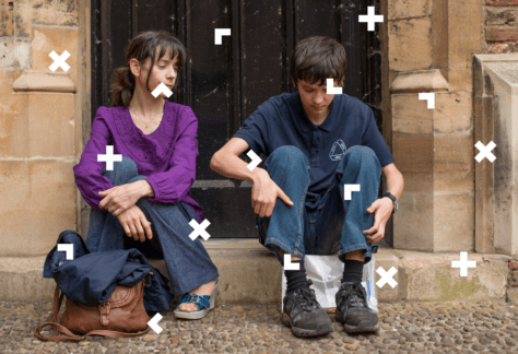 Dziewczyna i chłopak siedzą na schodach przed drzwiami. Dziewczyna patrzy na chłopaka. Przed dziewczyną leży torba i kurtka.