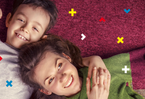 Na różowym dywanie leżą dziewczynka i chłopiec.