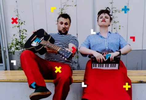 Kobieta i mężczyzna są jednakowo ubrani. Trzymają w rękach instrumenty.