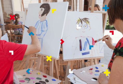 Dziecko i kobieta malują farbami na sztaludze.