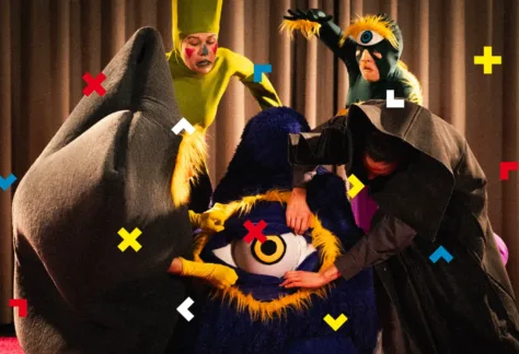 Aktorzy przebrani są w potwory i wskazują na materiałowe oko.