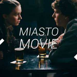 Kadr z filmu. Kobieta i mężczyzna siedzą przy stoliku i piją piwo. Napis: Miasto movie.