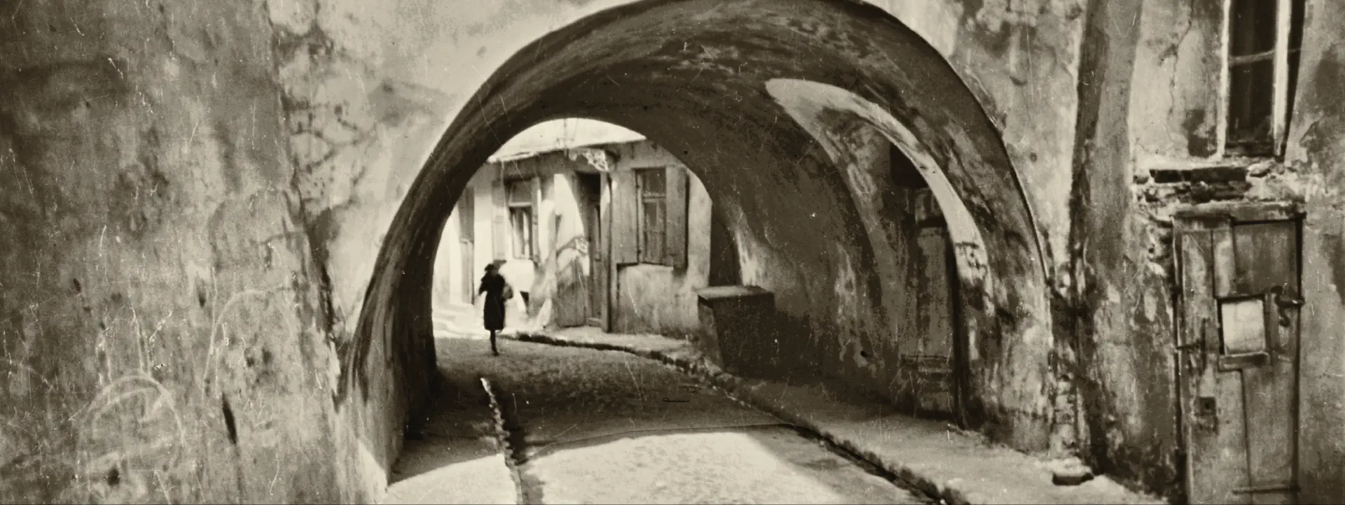 Czarno-białe zdjęcie bramy w Lublinie. Idzie nią kobieta.