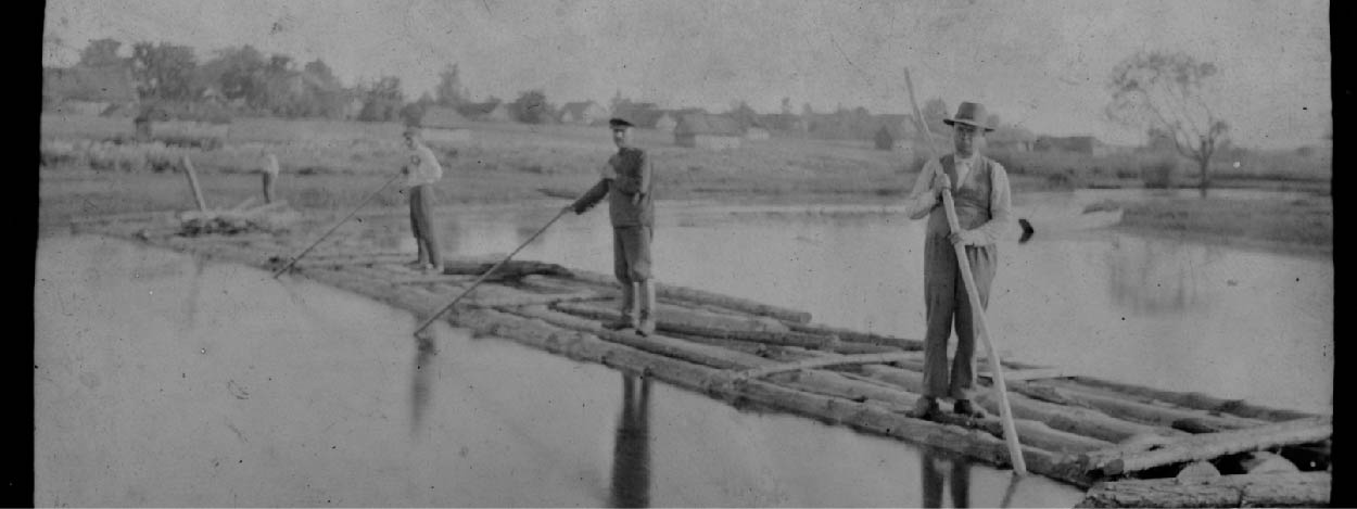Czarno-białe zdjęcie przedstawia mężczyzn płynących na tratwie.