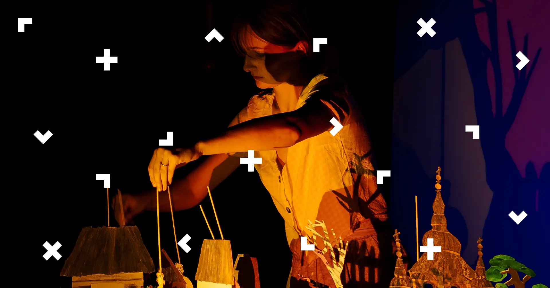 Kobieta porusza lalką na patyczku. Są tu domki i drzewa z kartonu. To zapowiedź spektaklu.