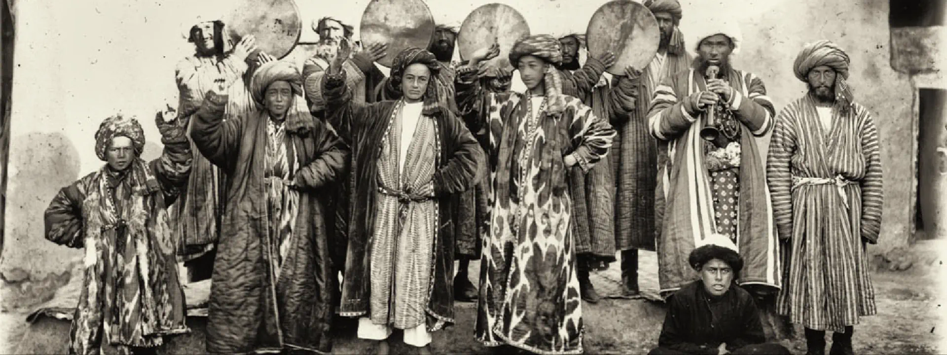 Czarno-białe zdjęcie grupy osób. To Azjaci. Stoją przed budynkiem.