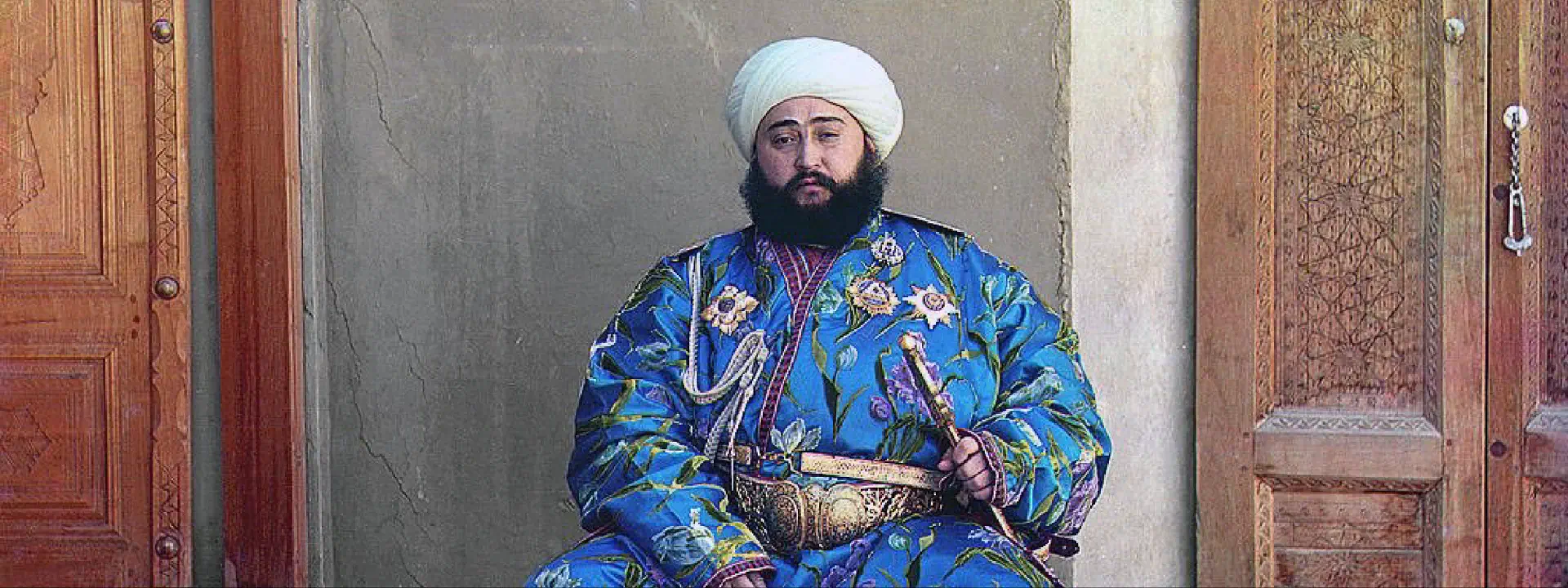 Przy drzwiach siedzi mężczyzna w turbanie na głowie.