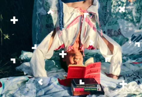 Mężczyzna stoi na głowie i czyta książkę do góry nogami.