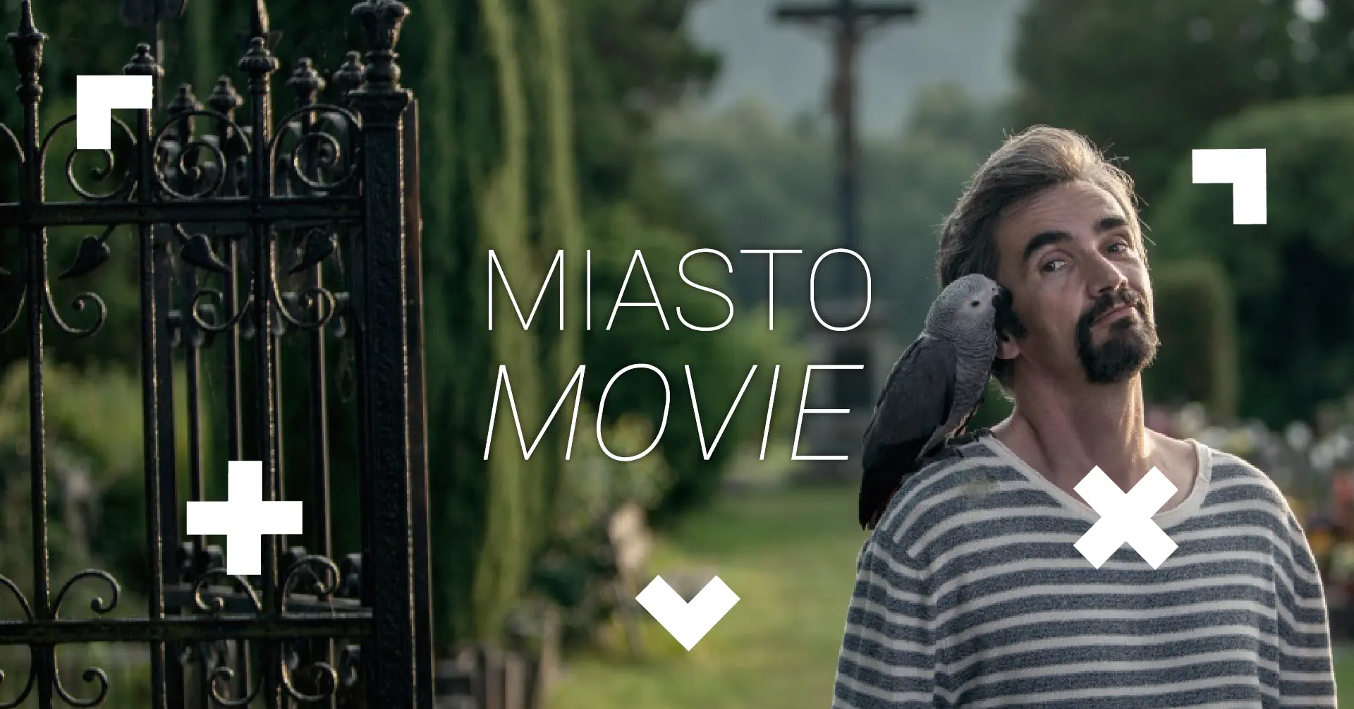 Mężczyzna ma na ramieniu papugę. Napis Miasto movie.