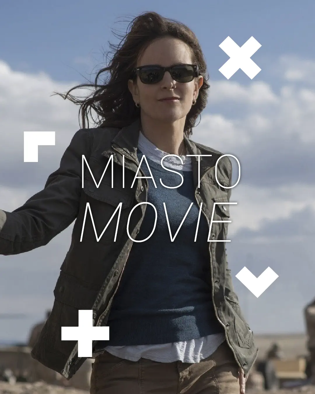 Kobieta w okularach uśmiecha się. Za nią stoi czołg. Na środku napis Miasto movie.