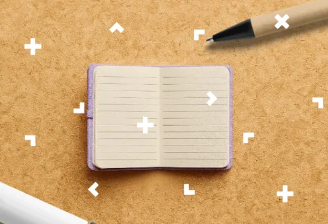 Na stole leży notes i długopis.