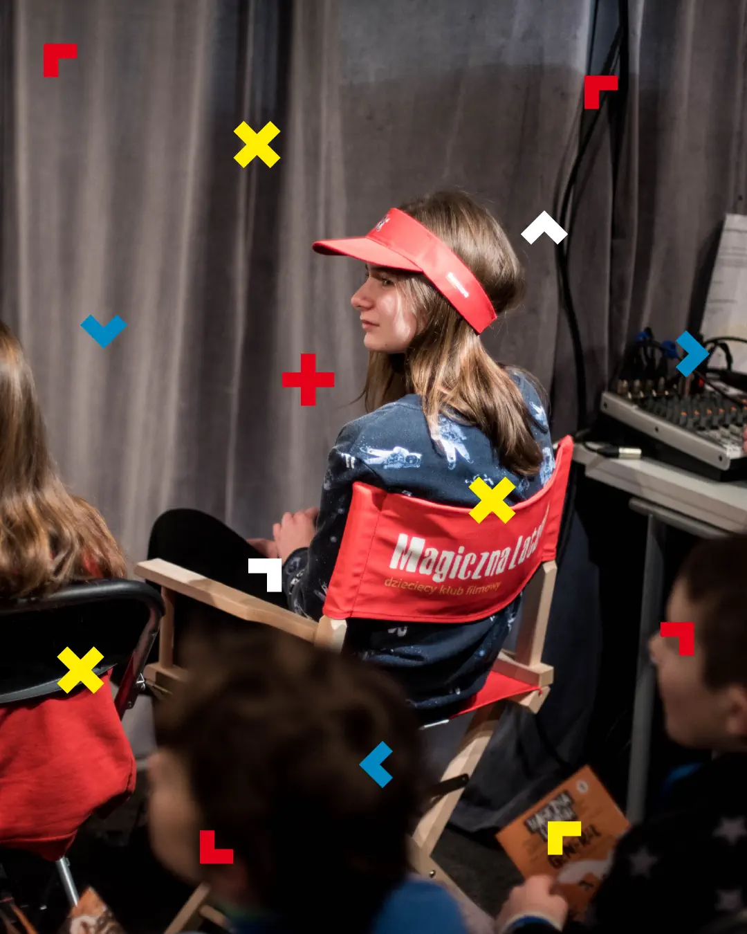 Dziewczyna siedzi na krześle z napisem Magiczna Latarnia. Ma też czapkę na głowie z tym samym napisem.