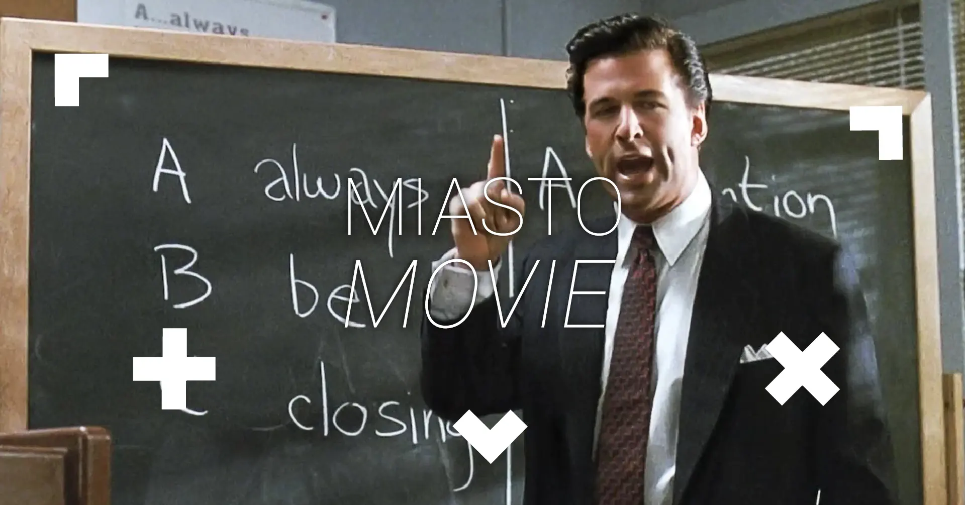 Mężczyzna stoi przy tablicy. Mówi i mocno gestykuluje.