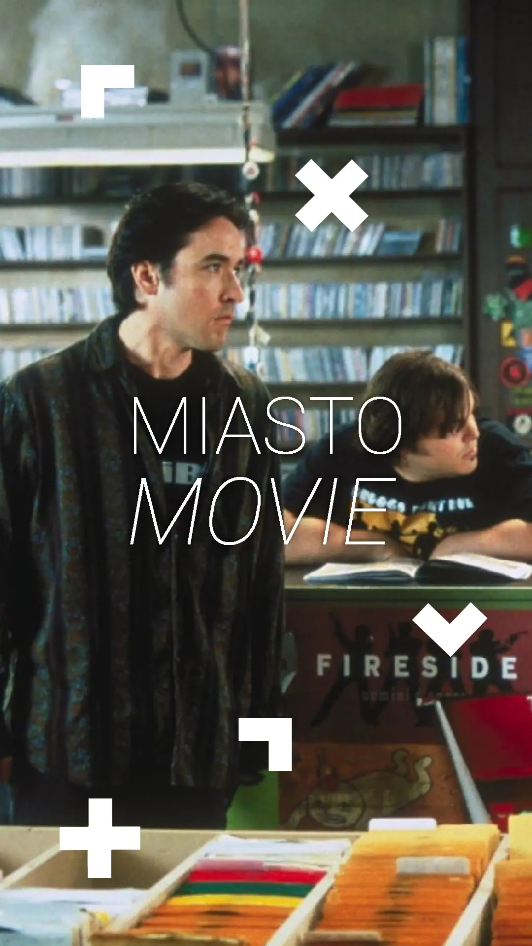 Mężczyzna stoi przy kasie i z kimś rozmawia. Napis: Miasto movie.