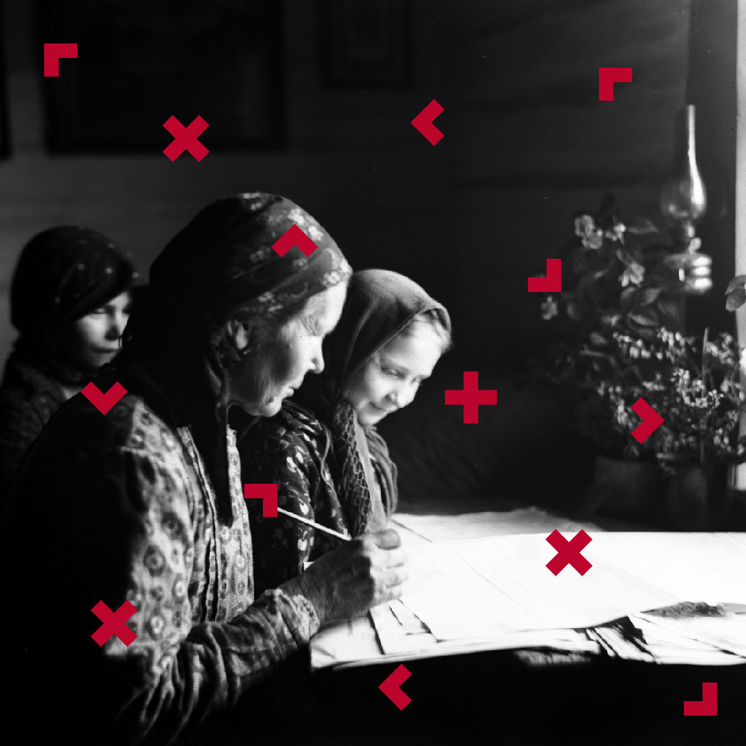 Kobieta z dwójką dzieci w strojach ludowych coś piszą na stole.