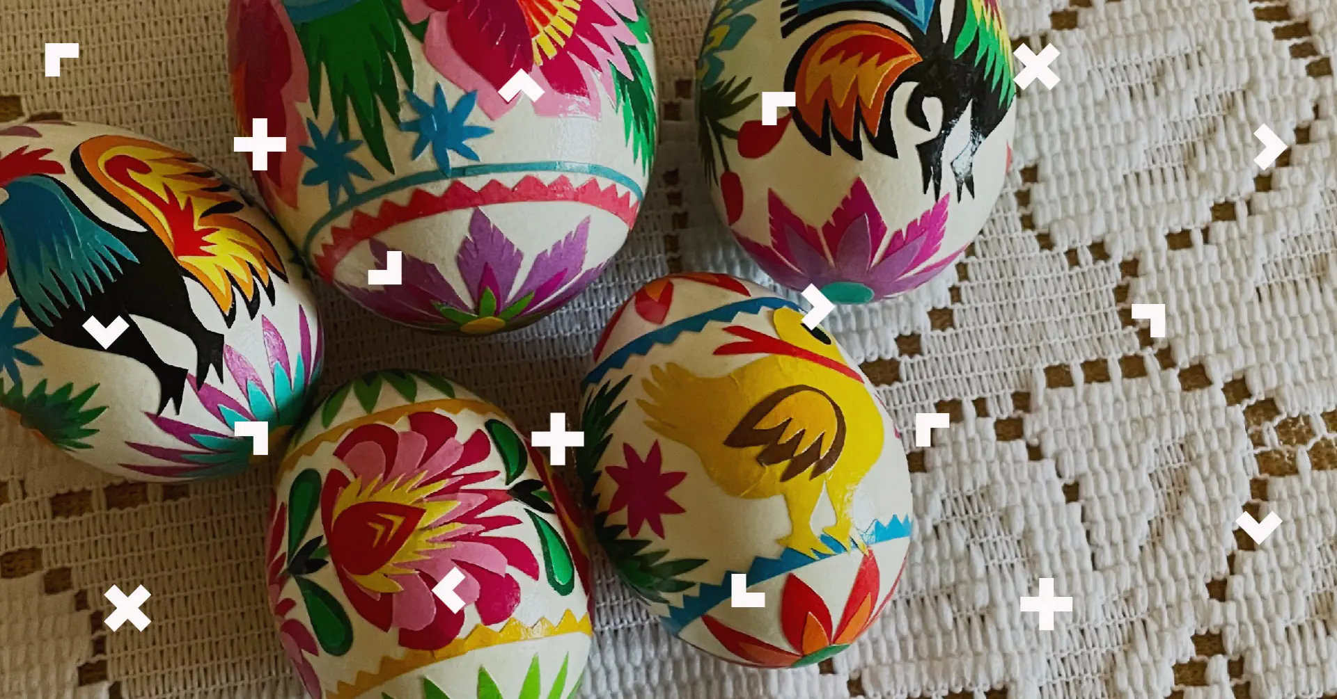 Pisanki wyklejane leżą na stole z białym obrusem.
