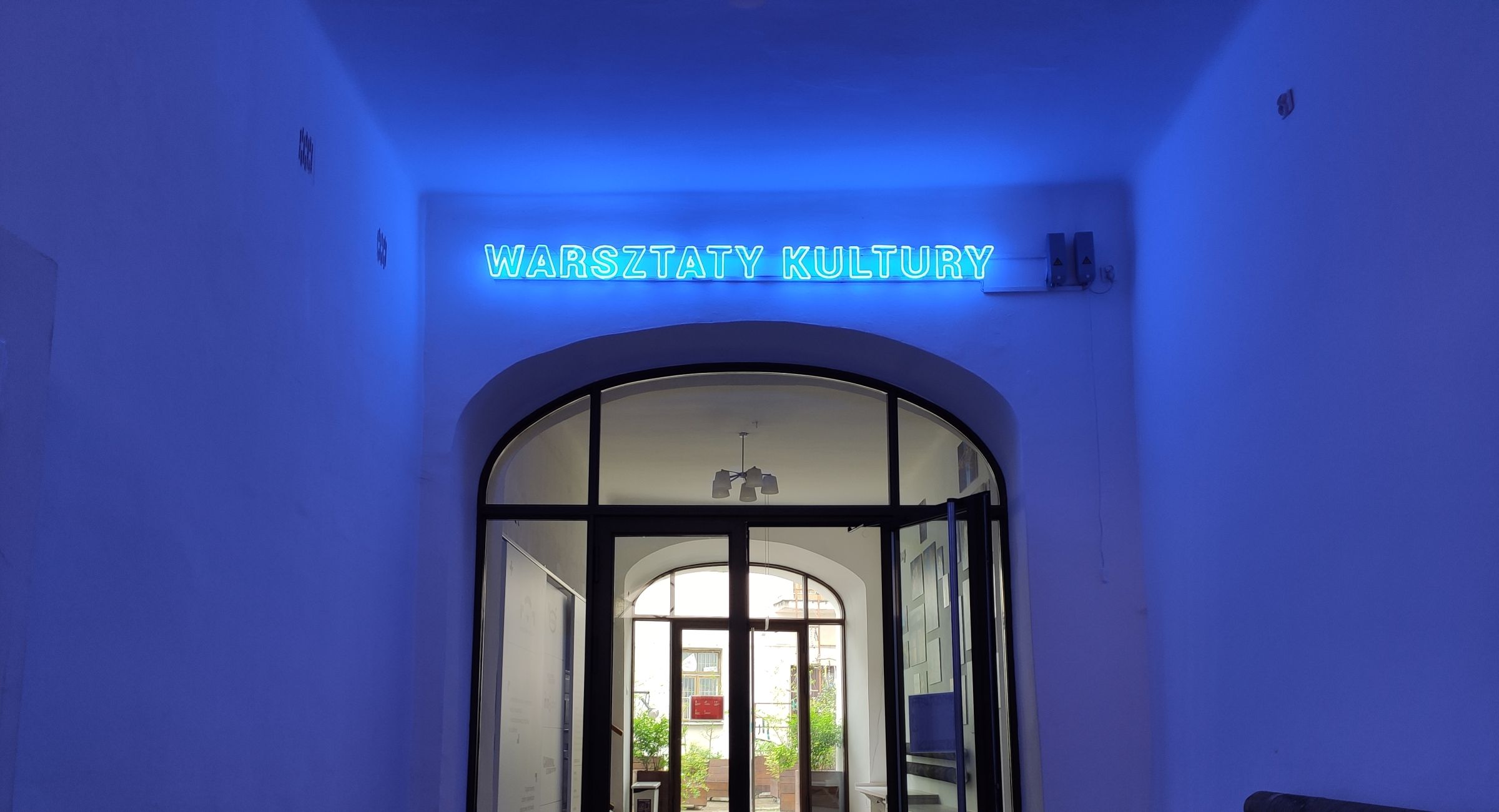 Wejście do Warsztatów Kultury podświetlone neonem.