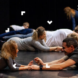 Dzieci z rodzicami trzymają się za ręce i turlają się po podłodze.