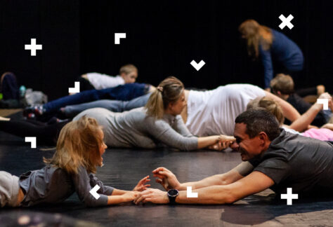 Dzieci z rodzicami trzymają się za ręce i turlają się po podłodze.