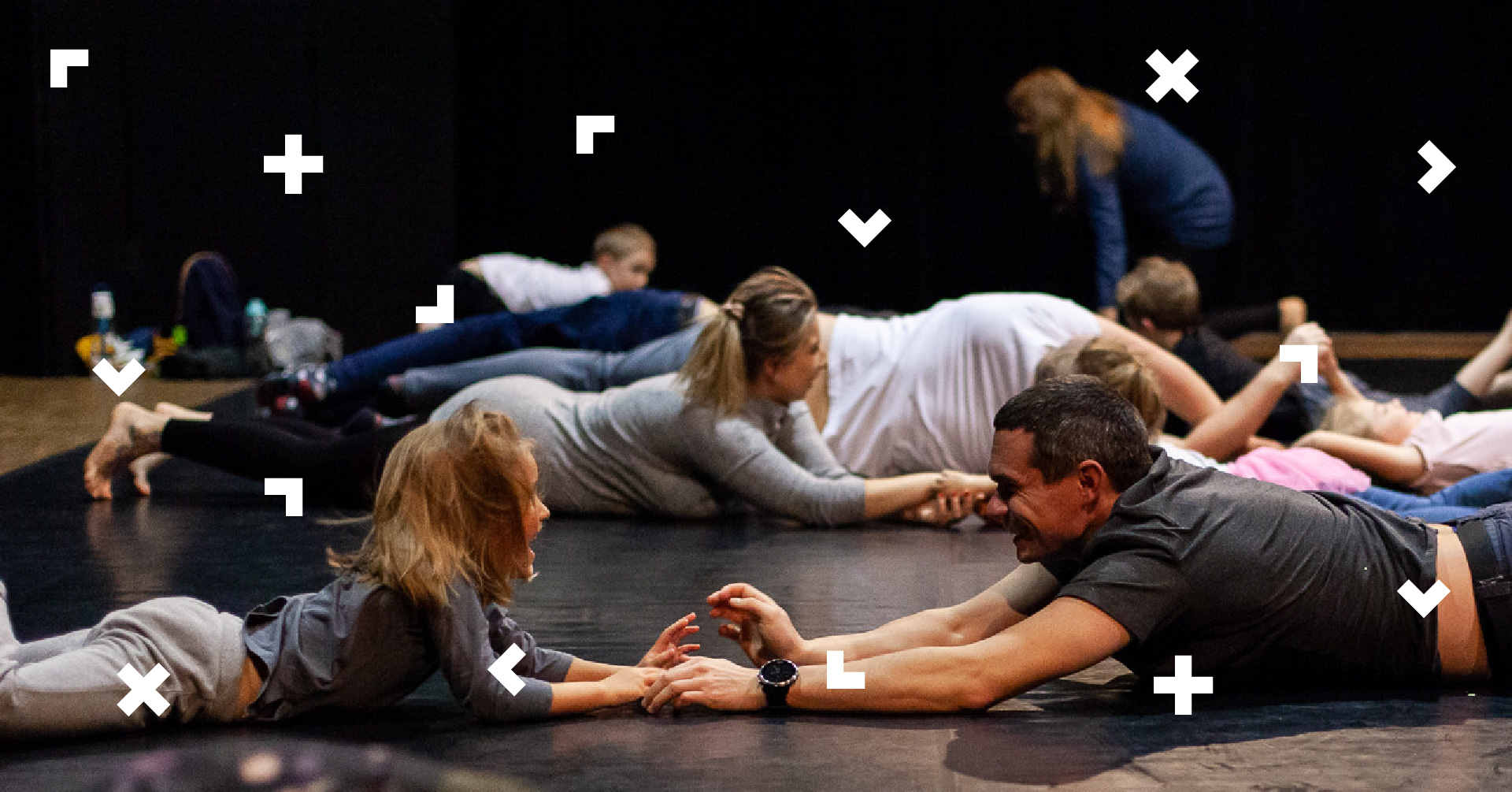 Dzieci z rodzicami trzymają się za ręce i turlają się po podłodze.