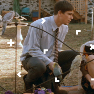 Chłopak i dziewczyna siedzą przed domem. Koło nich są papugi.