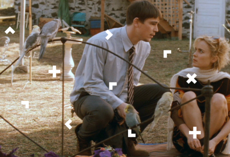 Chłopak i dziewczyna siedzą przed domem. Koło nich są papugi.