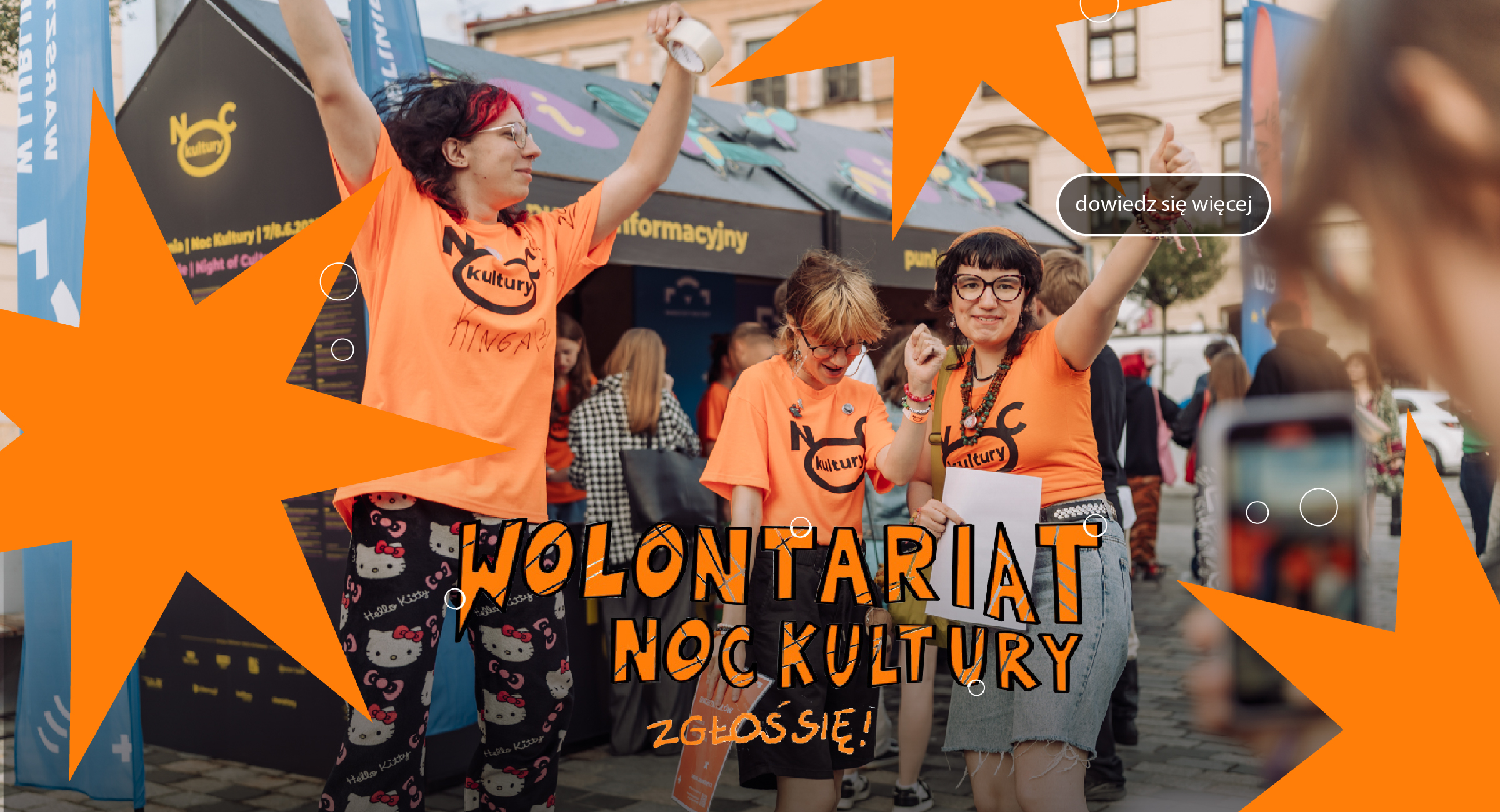 Grupa wolontariuszek podskakuje przed punktem informacyjnym.